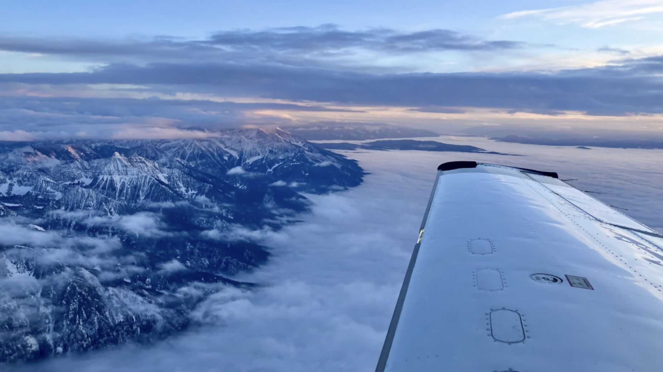 Airplane wing over mountain range